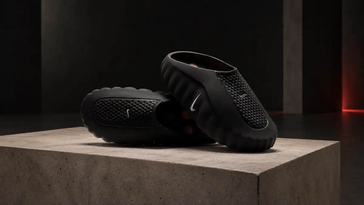 Black Nike Mind 001 mules with crimson sole nodes in a dark studio scene.